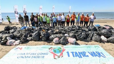 Ellerine eldivenlerini takan katılımcılar, sahilde biriken plastik atıklardan cam şişelere,